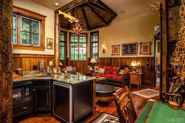 sitting room with sink, a notable chandelier, dark hardwood / wood-style flooring, vaulted ceiling, and wood walls