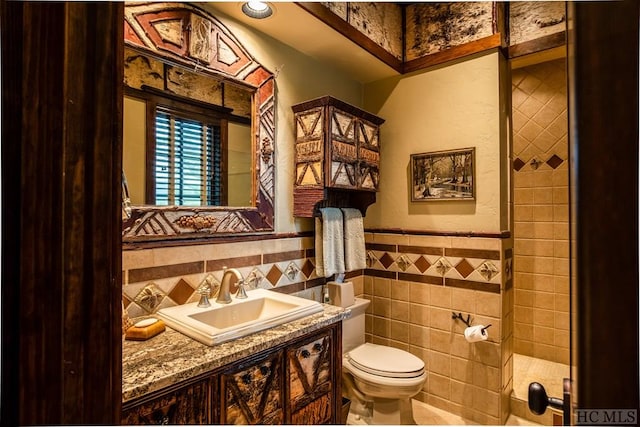 bathroom with tile walls, vanity, and toilet