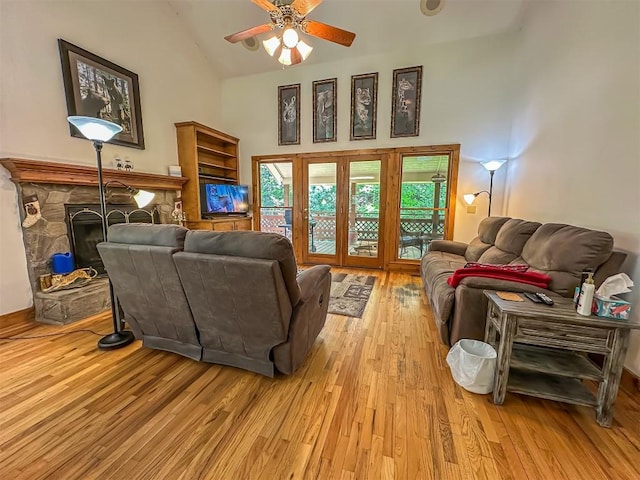 living area with light wood-style flooring, high vaulted ceiling, ceiling fan, and a fireplace