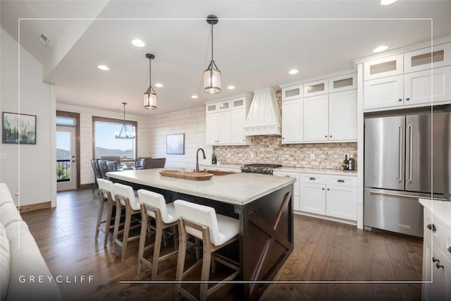 kitchen with dark wood-type flooring, premium range hood, light countertops, and high end fridge