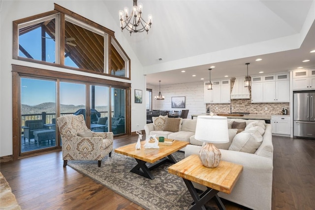 living area featuring high vaulted ceiling, dark wood-type flooring, a mountain view, and an inviting chandelier