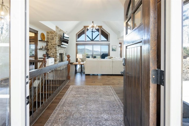 entrance foyer featuring high vaulted ceiling, a fireplace, wood finished floors, and a notable chandelier