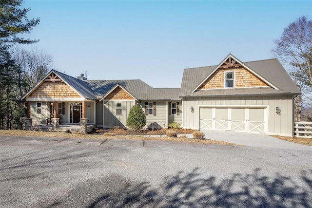 craftsman-style home featuring metal roof, aphalt driveway, board and batten siding, and an attached garage