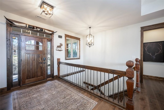 entrance foyer featuring baseboards, wood finished floors, visible vents, and an inviting chandelier