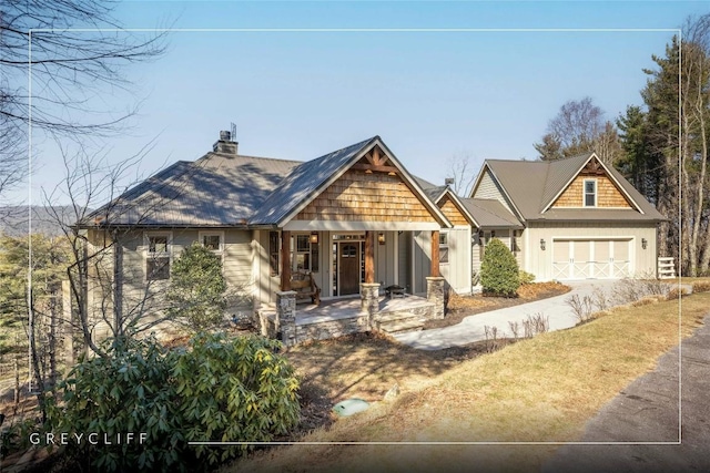 craftsman inspired home with an attached garage, a chimney, and a porch