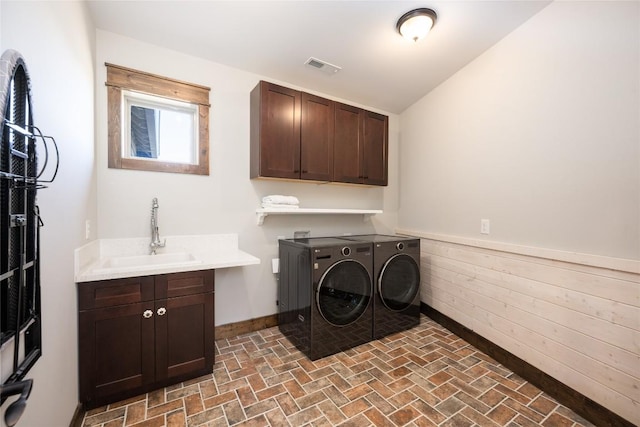 clothes washing area featuring a sink, visible vents, baseboards, cabinet space, and washing machine and clothes dryer