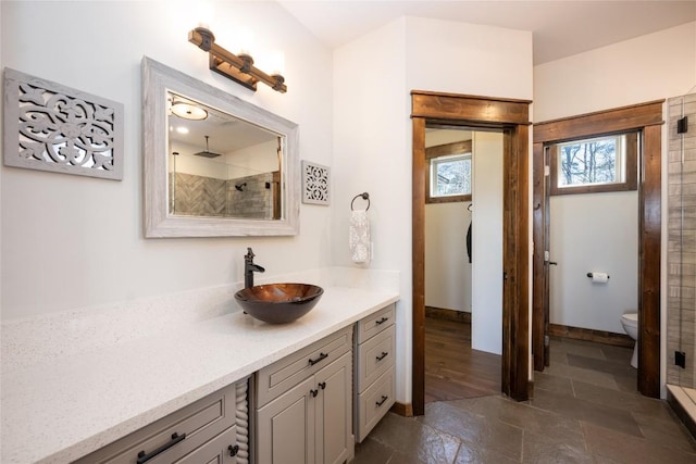 full bathroom with tiled shower, vanity, and toilet