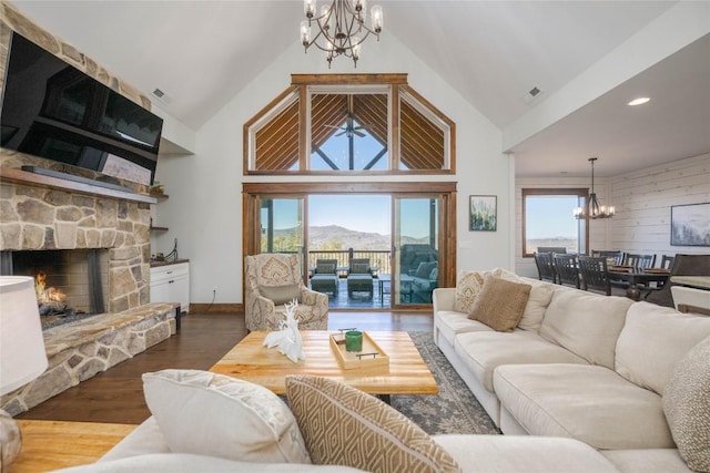 living area featuring a chandelier, a stone fireplace, wood finished floors, and a healthy amount of sunlight