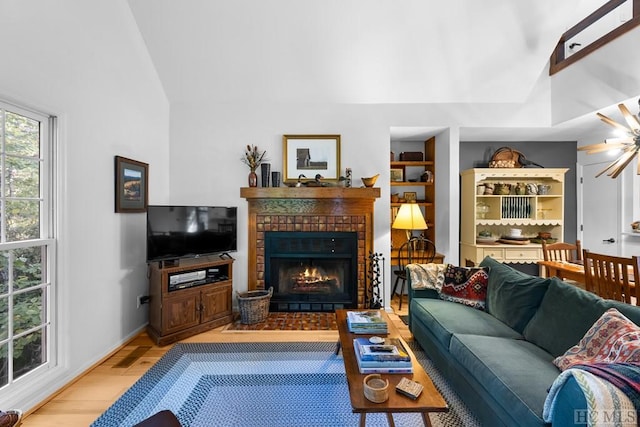 living room with ceiling fan, vaulted ceiling, a fireplace, and light hardwood / wood-style floors