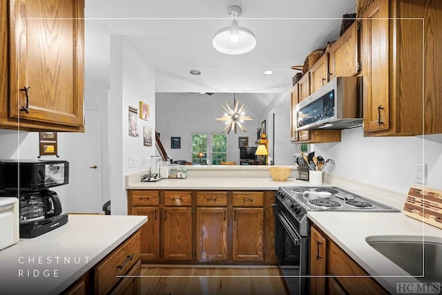 kitchen with electric stove, decorative light fixtures, kitchen peninsula, and sink