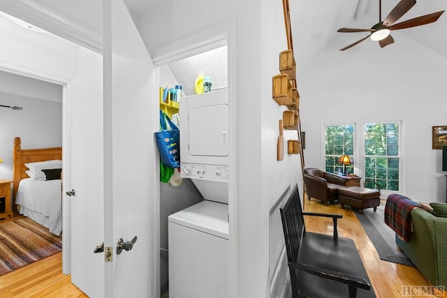 laundry area with stacked washer / dryer, ceiling fan, a towering ceiling, and light hardwood / wood-style floors