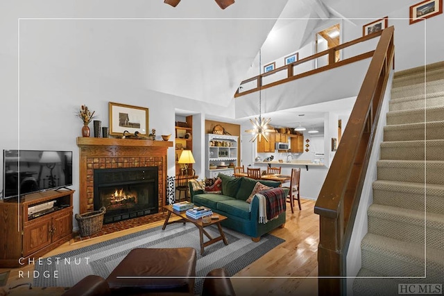 living area featuring high vaulted ceiling, built in shelves, a fireplace, wood finished floors, and stairs