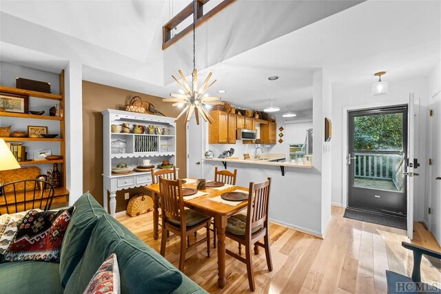 dining area with an inviting chandelier, sink, light hardwood / wood-style floors, and lofted ceiling