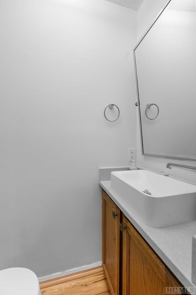 bathroom with vanity, toilet, hardwood / wood-style floors, and a textured ceiling