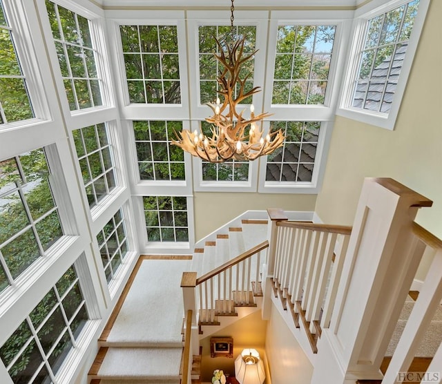 stairs with a healthy amount of sunlight, a notable chandelier, and a towering ceiling