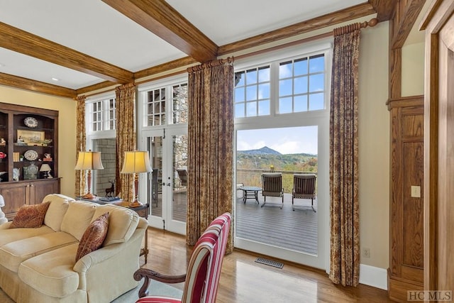 living room with beamed ceiling, a mountain view, light hardwood / wood-style floors, and french doors