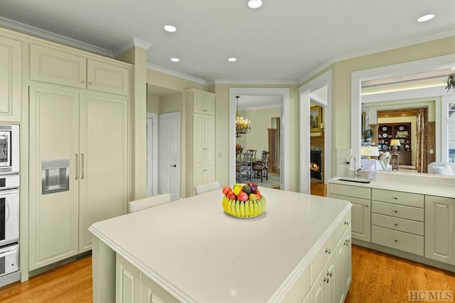 kitchen with ornamental molding, light hardwood / wood-style floors, sink, and a kitchen island