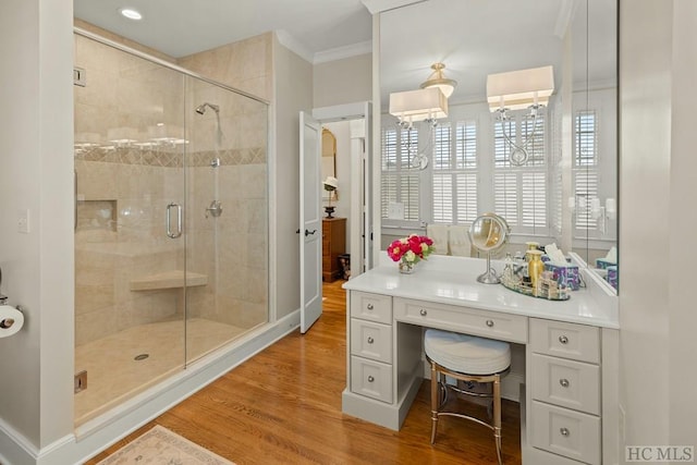 bathroom featuring crown molding, wood-type flooring, walk in shower, and vanity