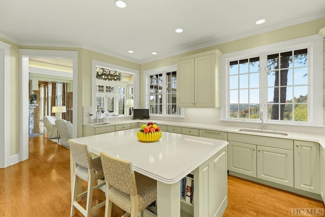 kitchen with sink, a kitchen breakfast bar, ornamental molding, and a center island