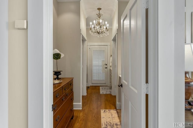 hall with wood-type flooring and an inviting chandelier