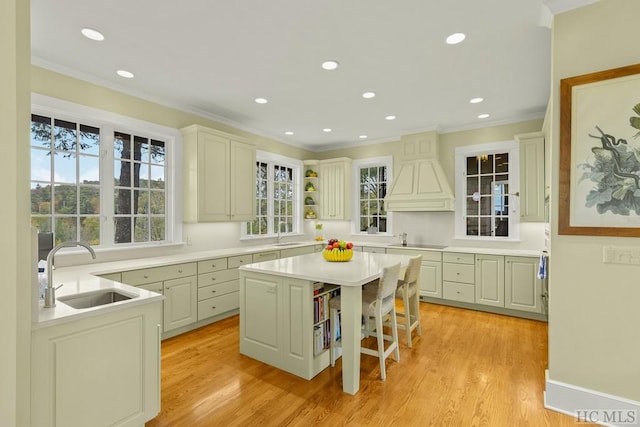 kitchen featuring sink, light hardwood / wood-style flooring, a breakfast bar, backsplash, and a center island