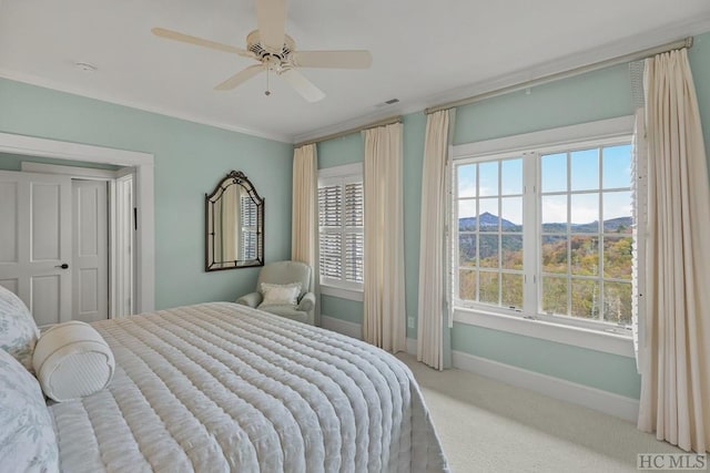 bedroom featuring multiple windows, a mountain view, light carpet, and ceiling fan