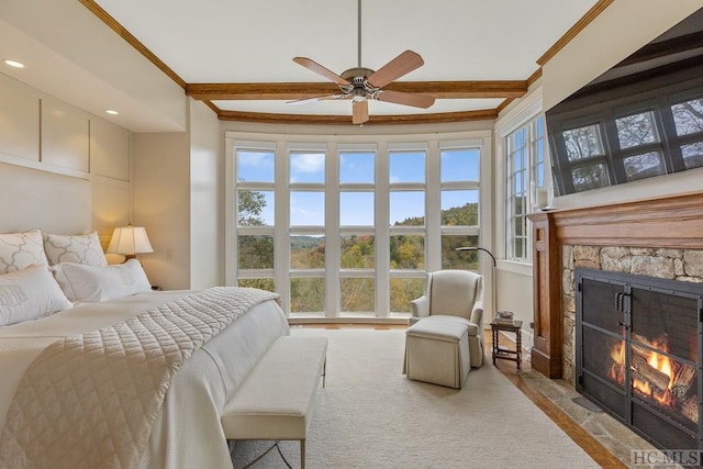 bedroom featuring beamed ceiling, ceiling fan, a fireplace, and multiple windows