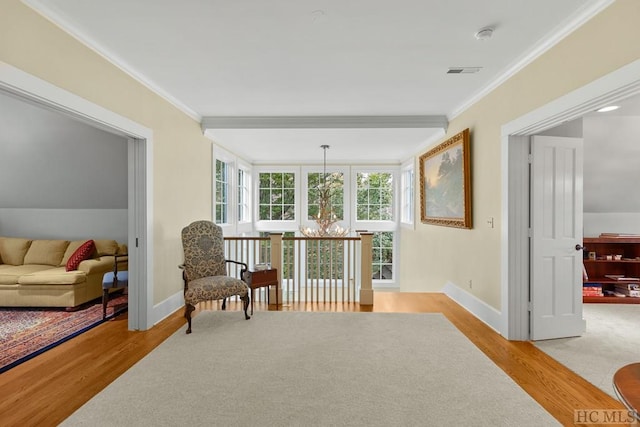 living area with crown molding, a chandelier, and light hardwood / wood-style floors