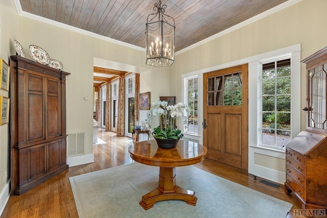 entrance foyer with hardwood / wood-style flooring, ornamental molding, a wealth of natural light, and wood ceiling