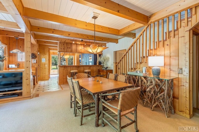 dining area with beamed ceiling, rail lighting, light carpet, and wooden walls