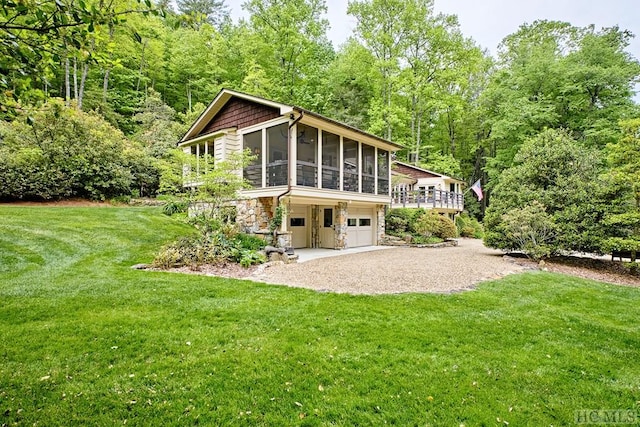 rear view of house featuring a garage, a sunroom, a yard, and a deck