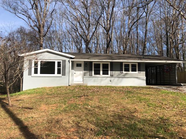 single story home featuring an attached carport, a front yard, and stucco siding