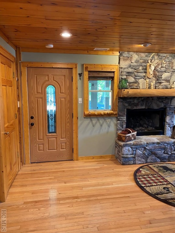 foyer with a stone fireplace, wooden ceiling, and light wood-type flooring