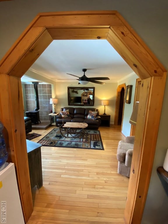 living room featuring ceiling fan, ornamental molding, and light hardwood / wood-style floors