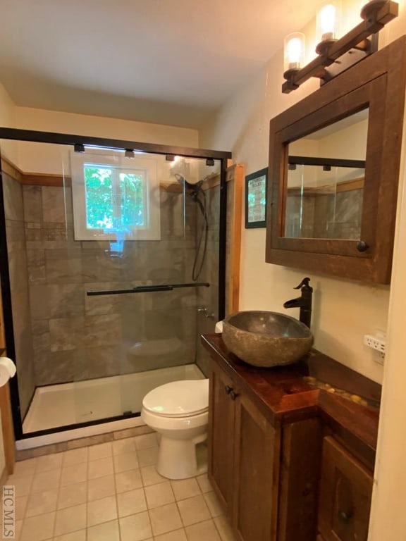 bathroom featuring tile patterned flooring, vanity, a shower with shower door, and toilet