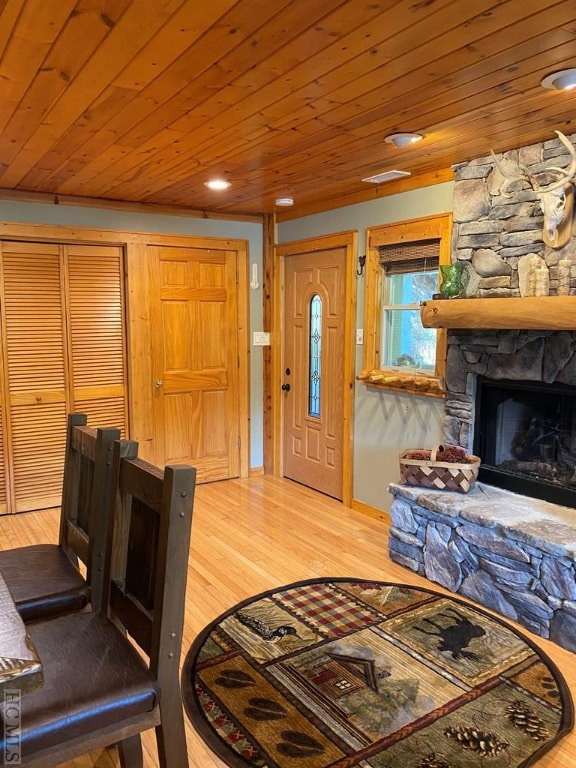 living room with a stone fireplace, wooden ceiling, and hardwood / wood-style flooring