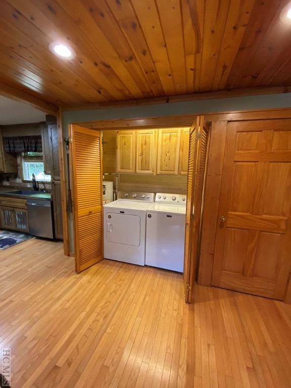 laundry area featuring sink, washer and clothes dryer, cabinets, and light wood-type flooring