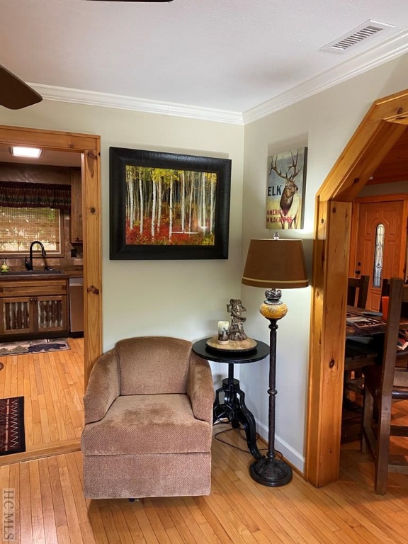 living area featuring hardwood / wood-style flooring, ornamental molding, and sink