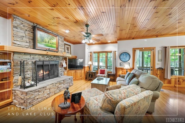 living room featuring crown molding, a fireplace, wooden walls, and light hardwood / wood-style floors