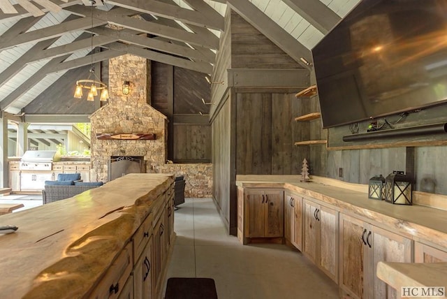 kitchen featuring vaulted ceiling with beams, pendant lighting, wood counters, and wood walls