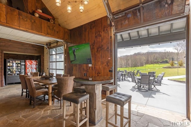 dining area with lofted ceiling and wood walls