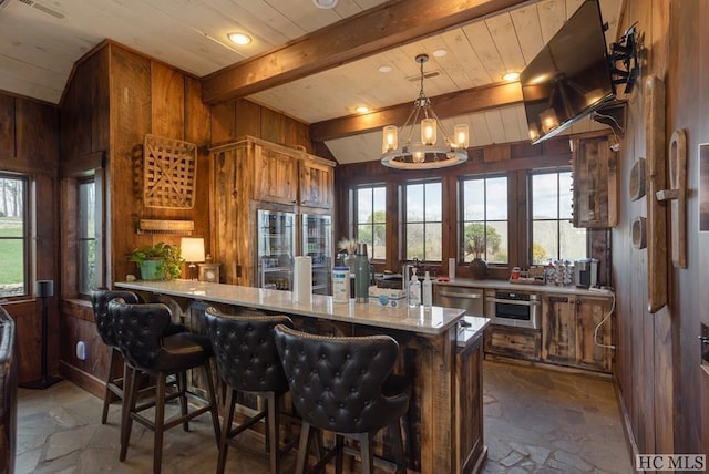 kitchen featuring an inviting chandelier, wooden walls, kitchen peninsula, and appliances with stainless steel finishes