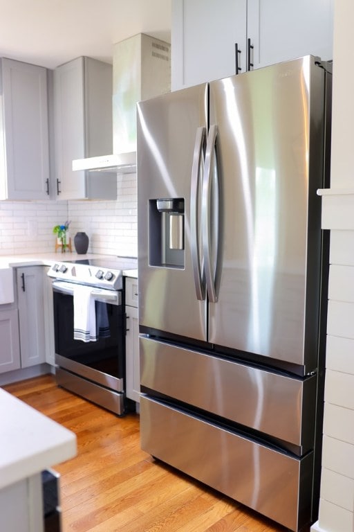 94 Breezy Knob Rd, Franklin, NC 28734 - kitchen featuring stainless steel appliances, gray cabinets, wall chimney exhaust hood, light wood-style flooring, and light countertops