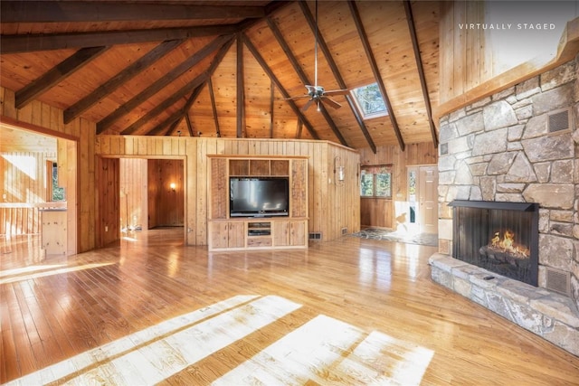 334 Back Nine Ln, Sapphire, NC 28774 - unfurnished living room featuring high vaulted ceiling, hardwood / wood-style floors, wooden walls, a stone fireplace, and a skylight
