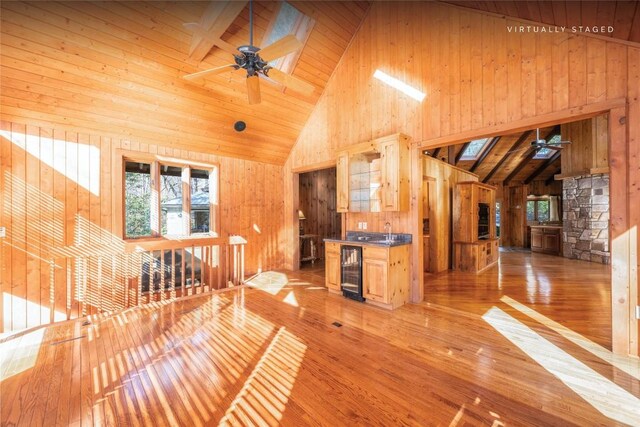 334 Back Nine Ln, Sapphire, NC 28774 - unfurnished living room with high vaulted ceiling, a ceiling fan, wine cooler, wood walls, and light wood-style floors