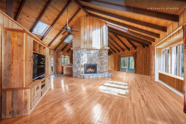 334 Back Nine Ln, Sapphire, NC 28774 - unfurnished living room with hardwood / wood-style flooring, a fireplace, a skylight, wooden walls, and ceiling fan