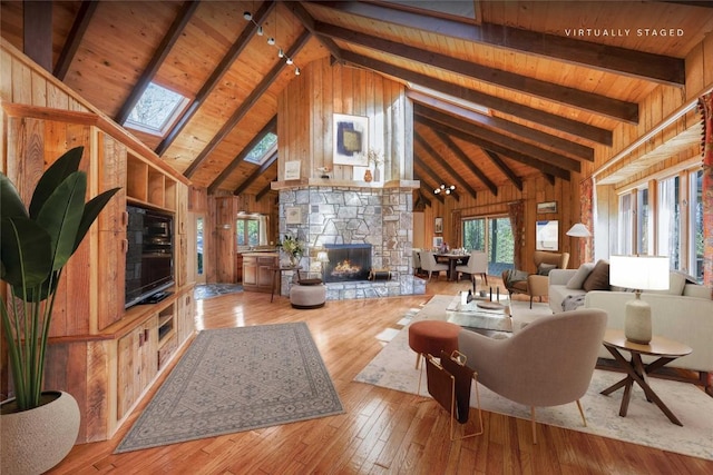334 Back Nine Ln, Sapphire, NC 28774 - living room with a wood ceiling with exposed beams, a skylight, hardwood / wood-style flooring, wooden walls, and a stone fireplace