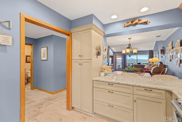 kitchen with light stone counters, cream cabinets, and pendant lighting