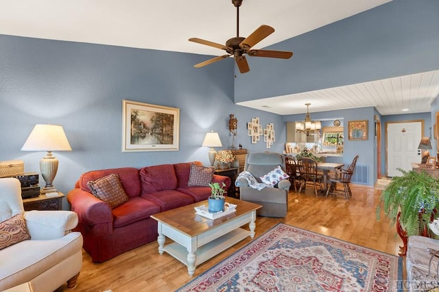 living room featuring ceiling fan with notable chandelier and light hardwood / wood-style floors