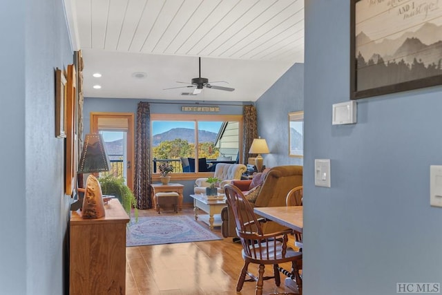 living room with wood ceiling, ceiling fan, wood-type flooring, a mountain view, and vaulted ceiling